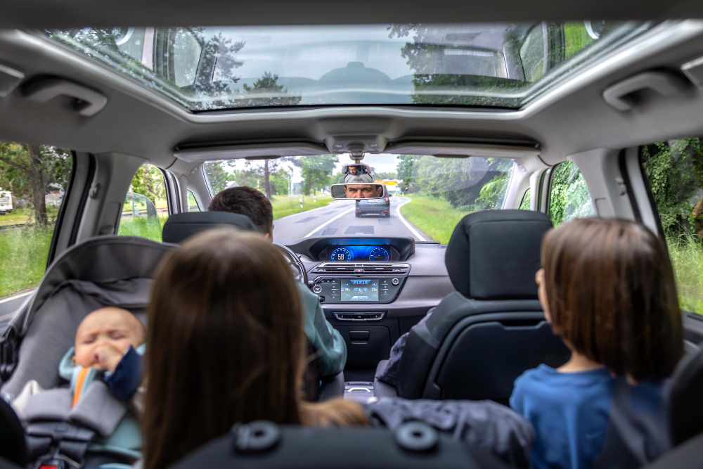 Vue intérieure spacieuse d'un SUV et grande familiale moderne sur une route de campagne, avec une famille et des enfants assis.
